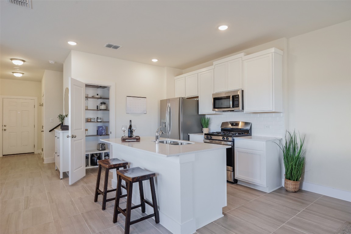 322 Furlong Drive Georgetown, TX 78626 - Photo 4 of 23 a kitchen with stainless steel appliances a microwave a stove a refrigerator a sink a dining table and chairs with wooden floor