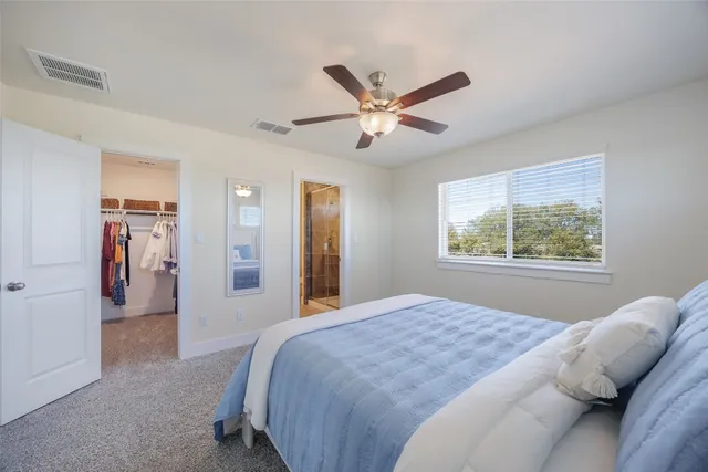 a bedroom with a large bed and a chandelier fan