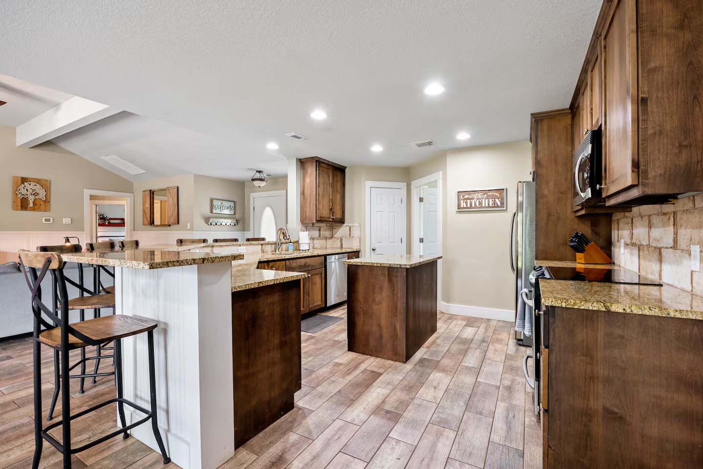 801 John Knox Road Fischer, TX 78623 - Photo 7 of 17 a kitchen with stainless steel appliances granite countertop a refrigerator oven a sink dishwasher a dining table and chairs with wooden floor