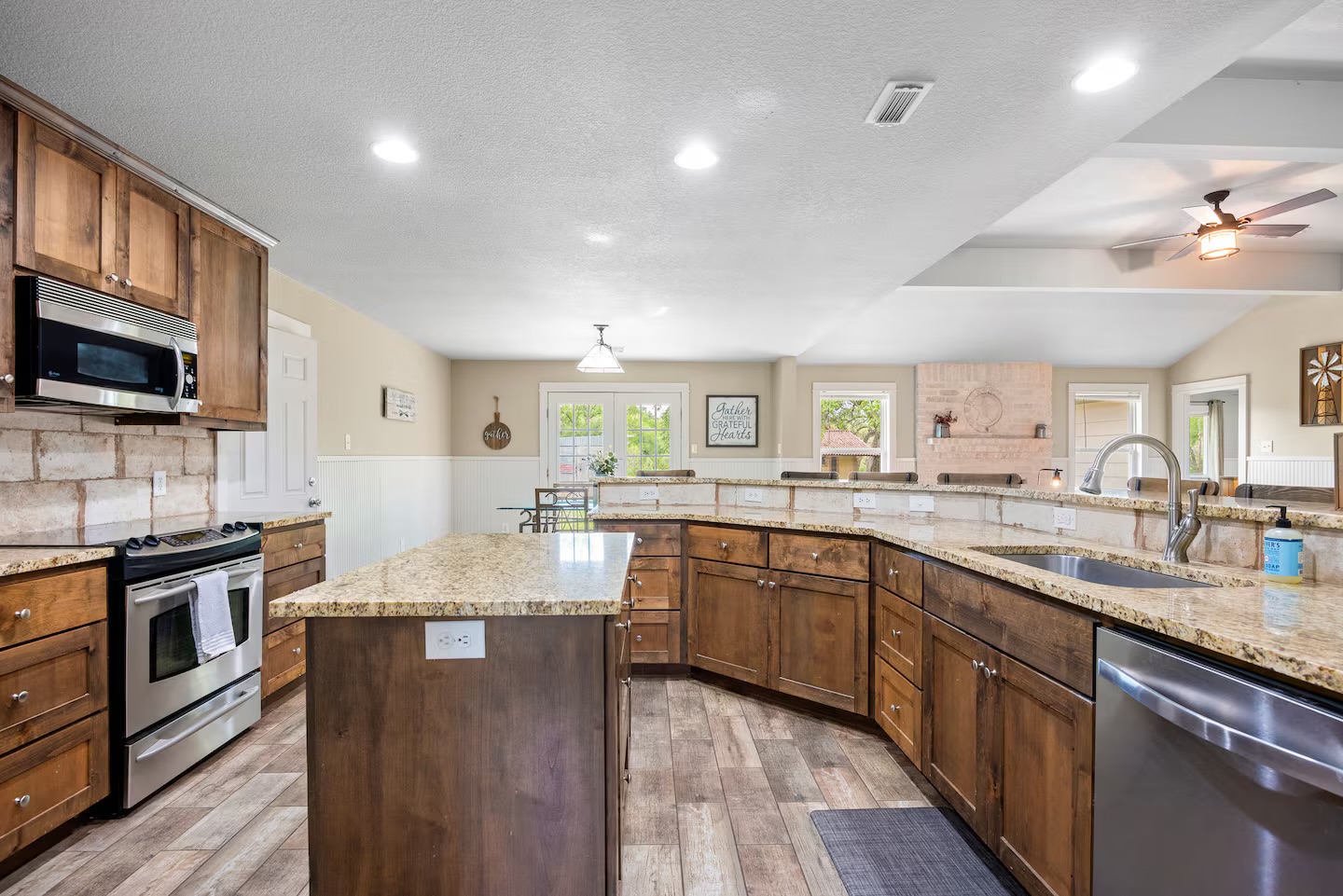 801 John Knox Road Fischer, TX 78623 - Photo 8 of 17 a large kitchen with stainless steel appliances granite countertop a sink dishwasher stove top oven and wooden cabinets