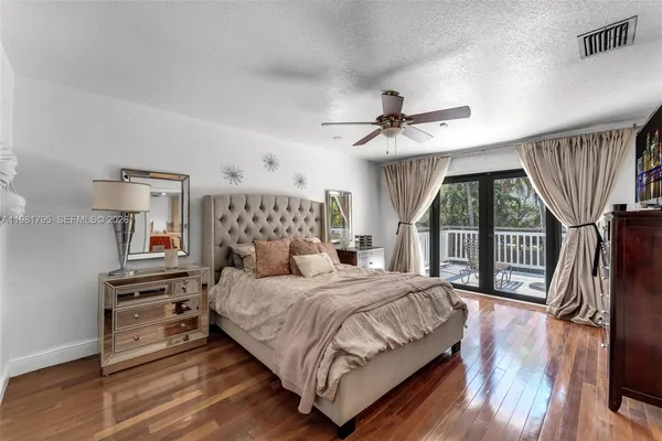 a bedroom with a bed a couch and a large window with wooden floor