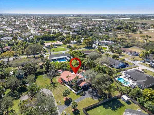 an aerial view of residential houses with outdoor space and trees