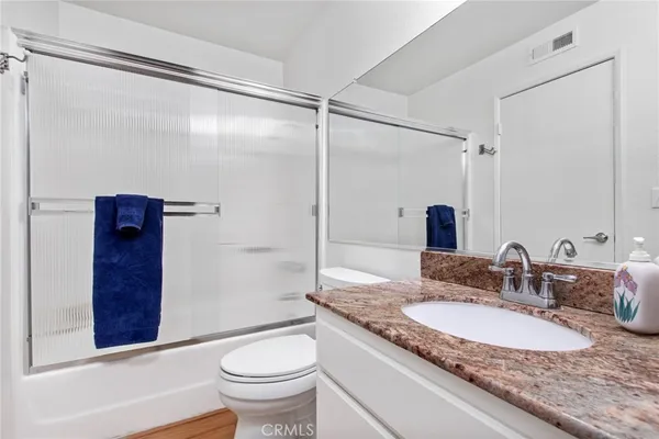 a bathroom with a granite countertop sink toilet and shower