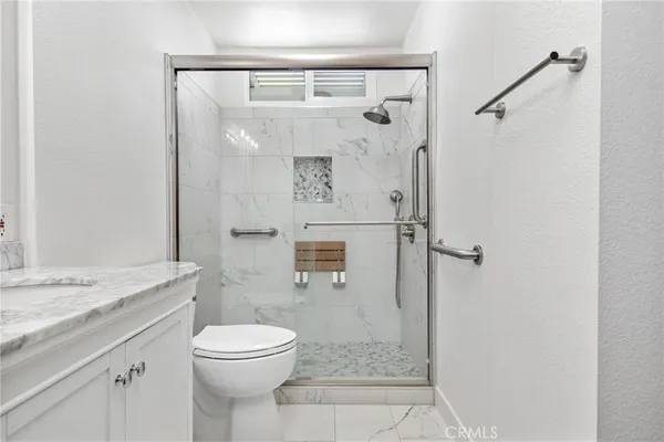 a bathroom with a granite countertop shower a toilet and a sink