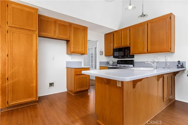 a kitchen with stainless steel appliances granite countertop wooden cabinets a stove top oven a sink and dishwasher with wooden floor