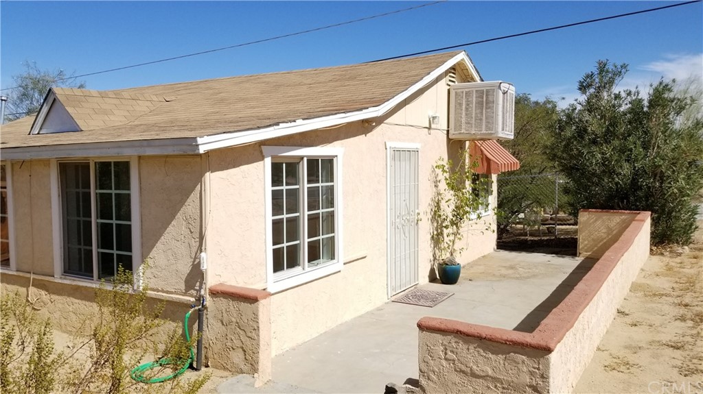 61750 Desert Air Road Joshua Tree, CA 92252 - Photo 4 of 28 a front view of a house with a yard and garage