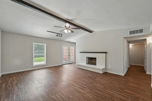 an empty room with wooden floor fireplace and windows