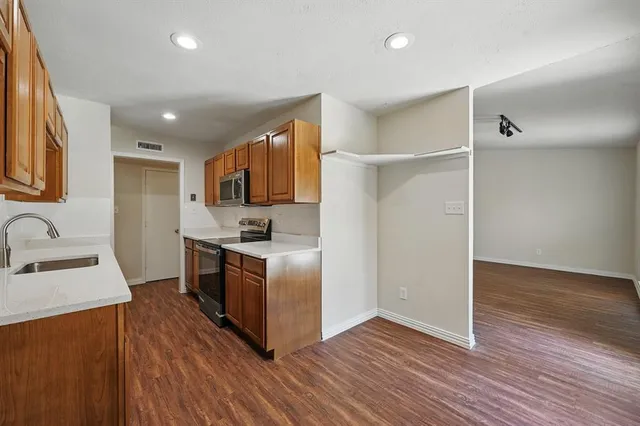 a kitchen with stainless steel appliances granite countertop a refrigerator a sink dishwasher a stove with wooden floors and a fireplace