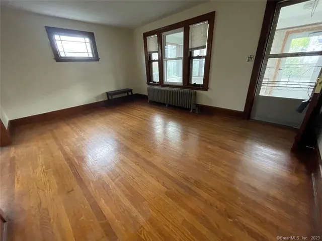 a view of an empty room with wooden floor and windows