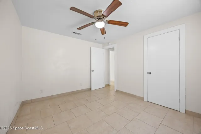 an empty room with ceiling fan and window