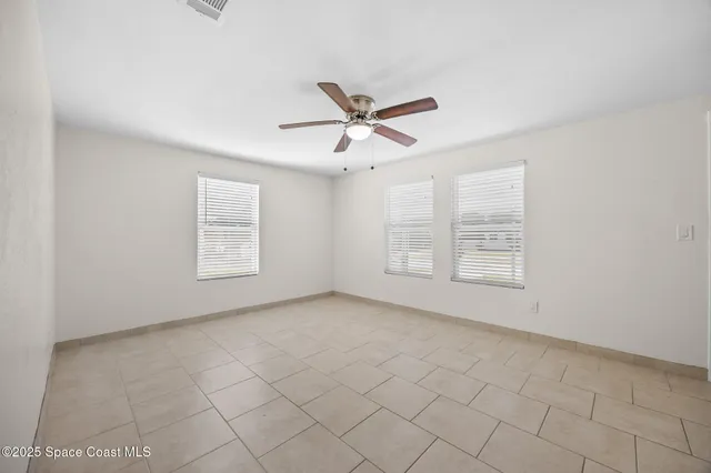 an empty room with windows and fan