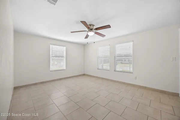 an empty room with windows and fan