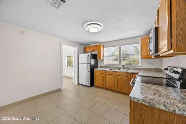 a kitchen with granite countertop a refrigerator and a stove top oven