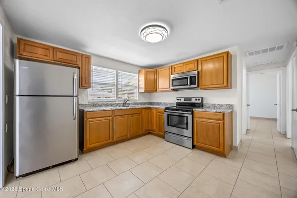 a kitchen with granite countertop a refrigerator stove top oven and sink