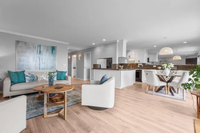 a living room with stainless steel appliances kitchen island granite countertop furniture and wooden floor