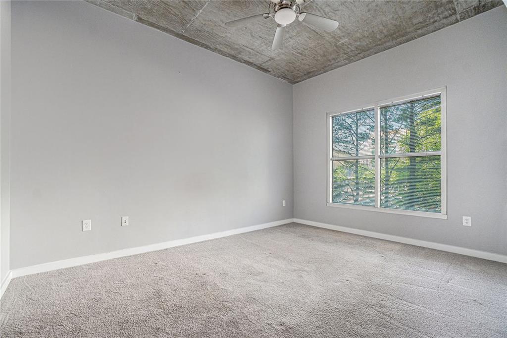 250 Pharr Road Northeast, Unit 405 Atlanta, GA 30305 - Photo 10 of 20 an empty room with a chandelier fan and windows