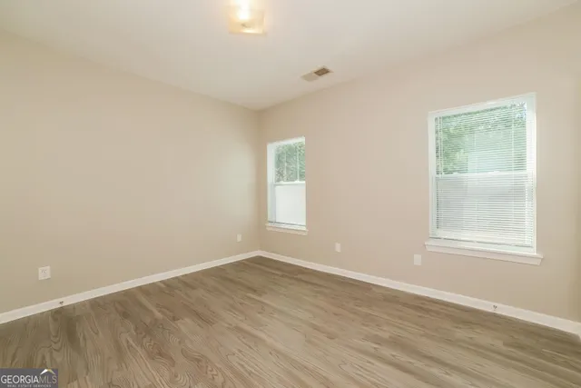 an empty room with wooden floor and windows