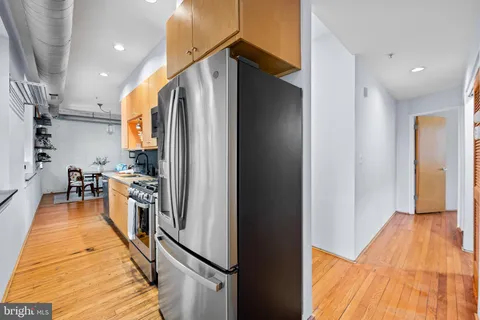 a kitchen with stainless steel appliances granite countertop a refrigerator and a wooden floor