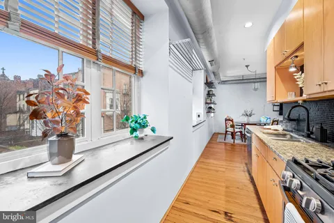 a large kitchen with stainless steel appliances granite countertop a sink a stove and a wooden floor