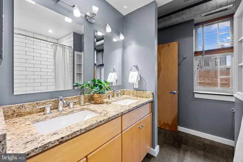 a bathroom with a granite countertop sink and a mirror