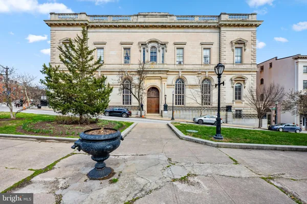 a front view of a building with a garden and plants