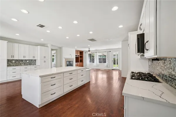 a kitchen with stainless steel appliances kitchen island granite countertop a stove and a white cabinets