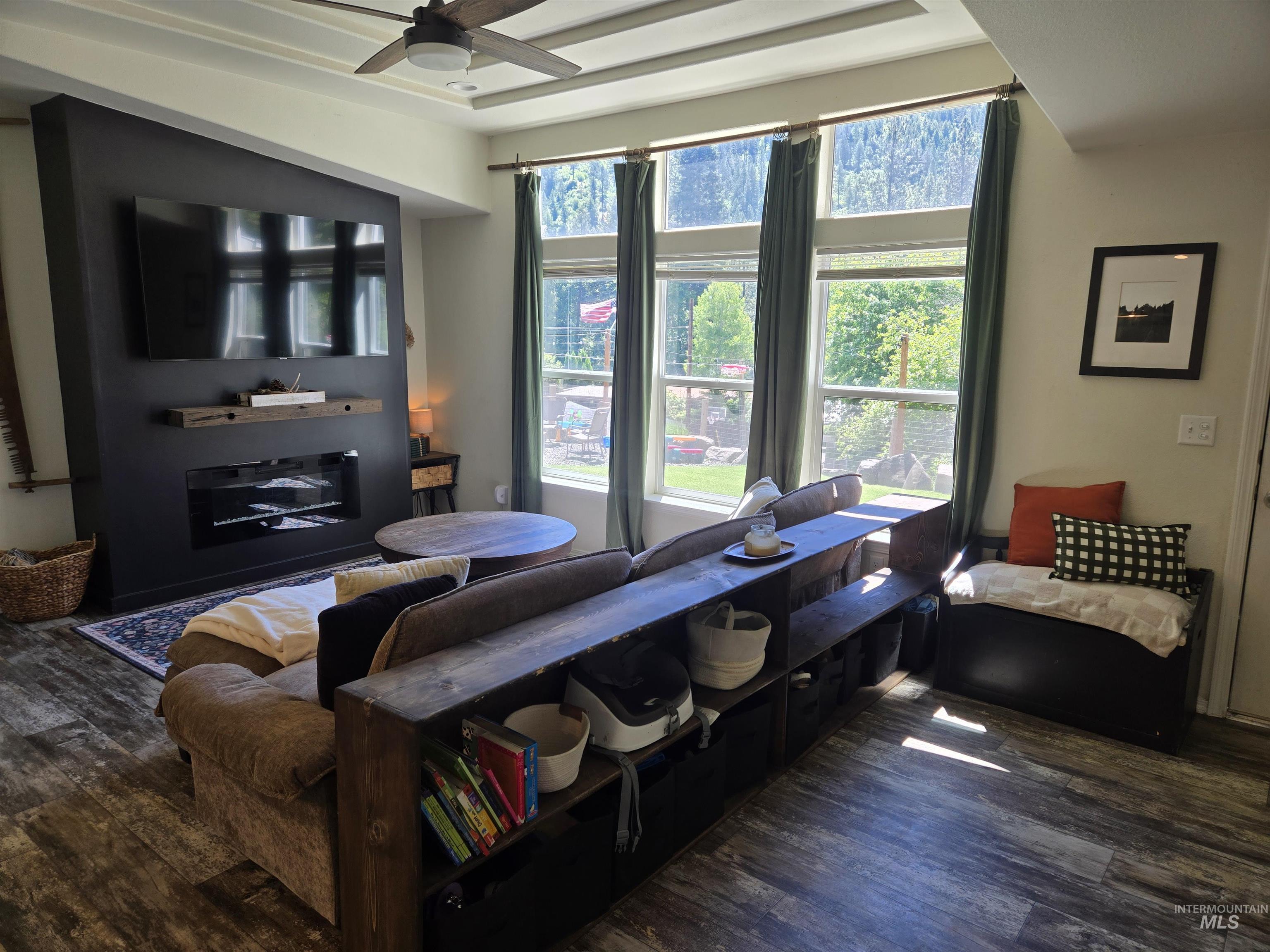 174 Konkolville Road Orofino, ID 83544 - Photo 6 of 43 Open-concept living area featuring a modern fireplace with a wooden mantel, wood-finish flooring, and a coffered ceiling with a ceiling fan