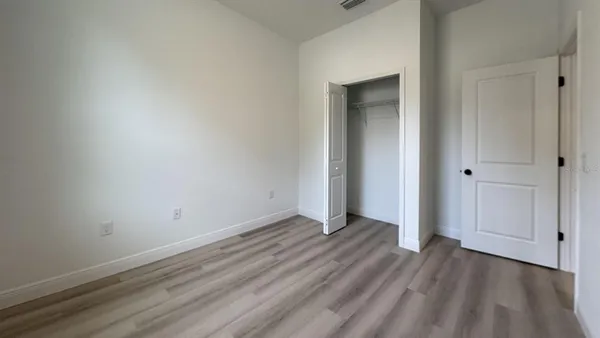 a view of an empty room with closet and a window