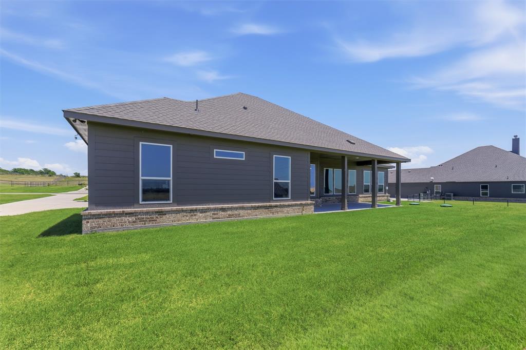 114 Hillview Trail Decatur, TX 76234 - Photo 26 of 27 Spacious rear exterior featuring gray siding, a covered patio, a brick foundation, large windows, and a generously sized lawn area