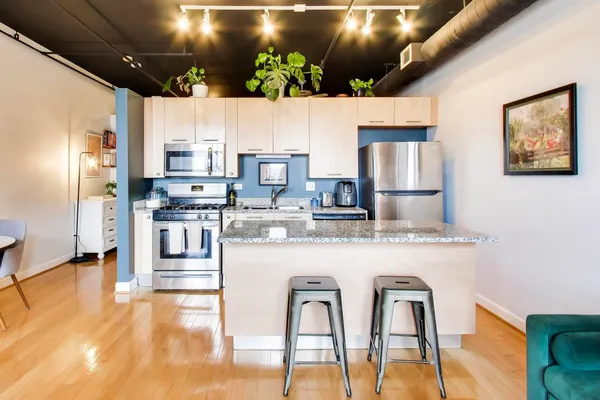 a kitchen with stainless steel appliances kitchen island granite countertop a refrigerator and microwave