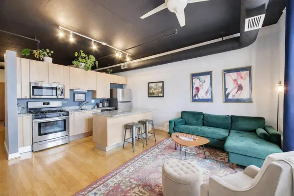 a living room with furniture kitchen view and a wooden floor
