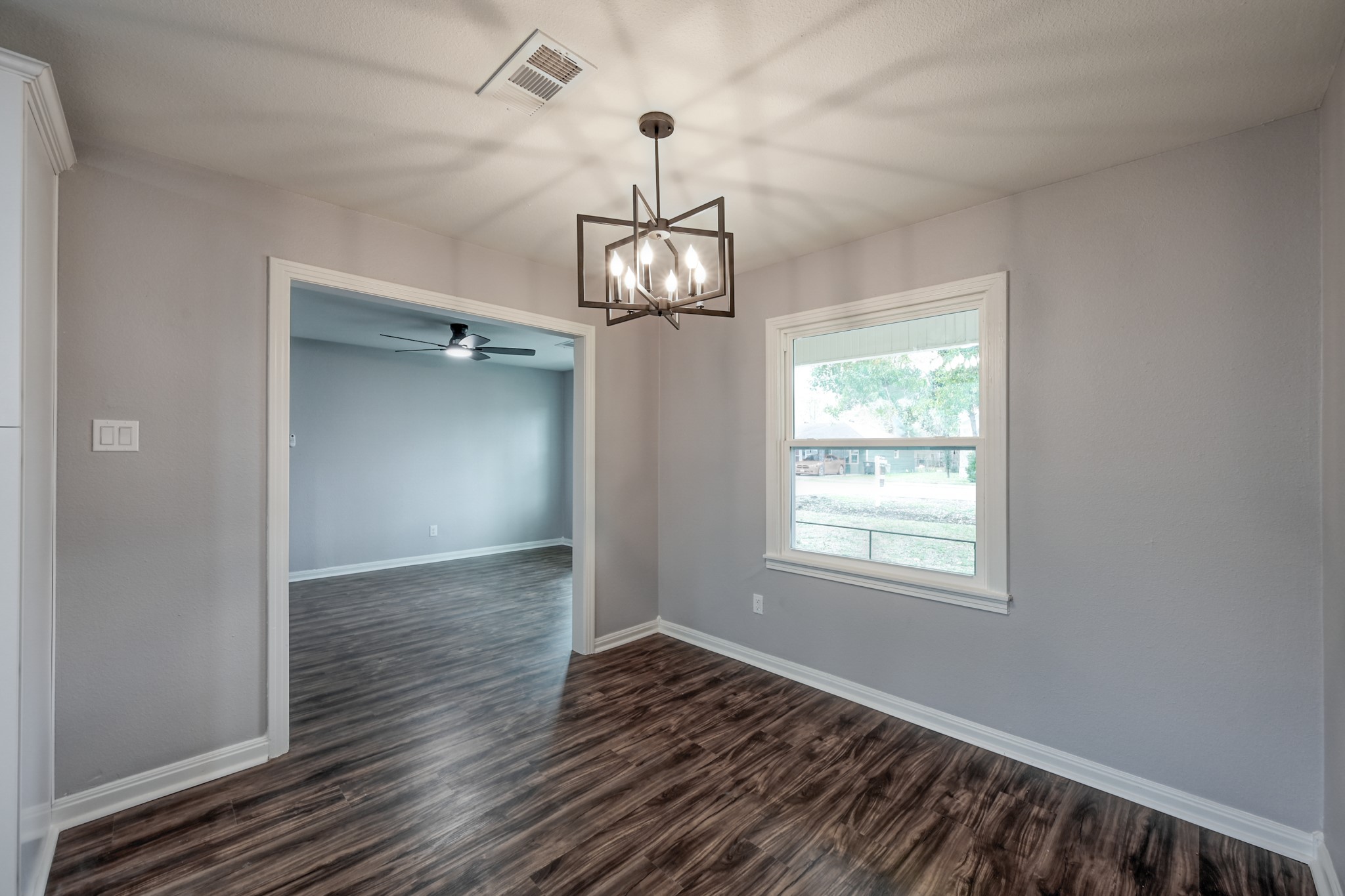 513 Barkley Street Houston, TX 77022 - Photo 26 of 48 This Formal Dining room features modern wood flooring and neutral gray walls. It has a stylish geometric light fixture and a large window that allows natural light. The space opens into Formal Living. room with a ceiling fan, creating a seamless flow between areas.