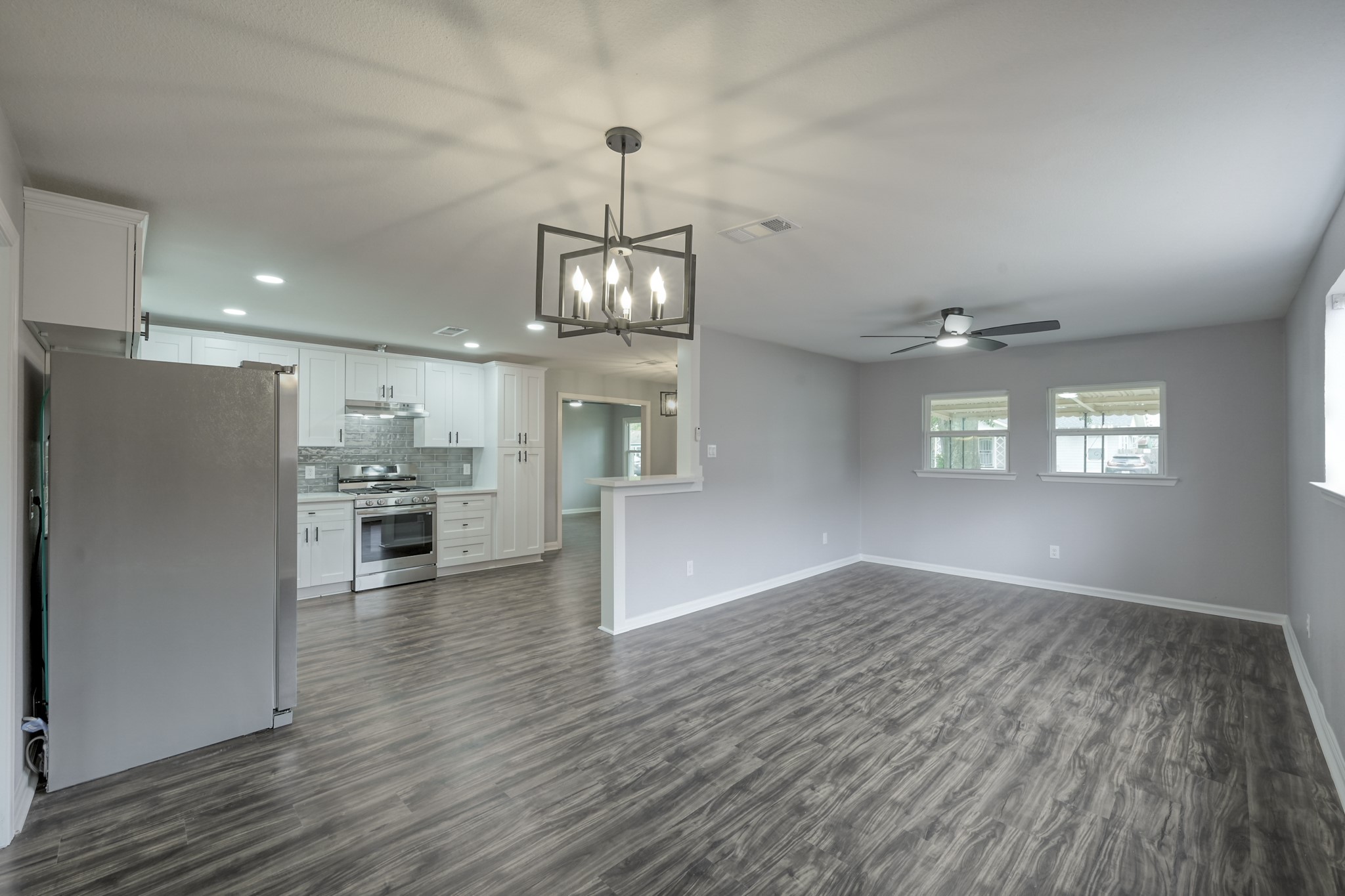 513 Barkley Street Houston, TX 77022 - Photo 38 of 48 This photo showcases a spacious open-concept living area with modern wood flooring, featuring a sleek kitchen with stainless steel appliances and white cabinetry. The room is well-lit with contemporary light fixtures and a ceiling fan, providing a comfortable breakfast and living area open-concept and stylish setting.