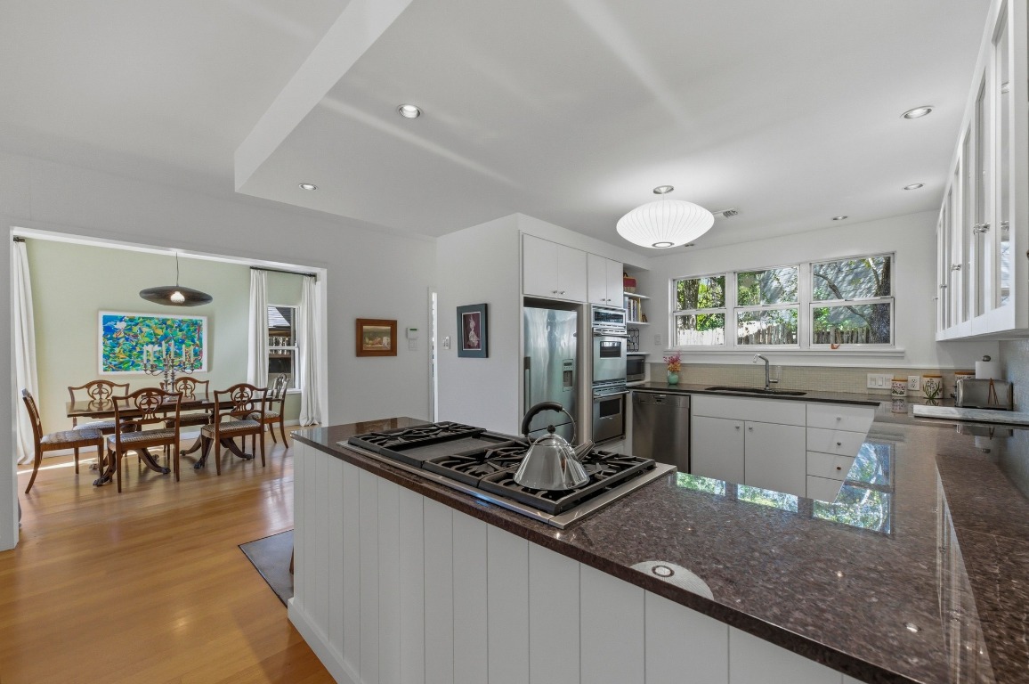 1712 West 10th Street Austin, TX 78703 - Photo 9 of 34 a kitchen with stainless steel appliances granite countertop a stove top oven a sink a dining table and chairs with wooden floor