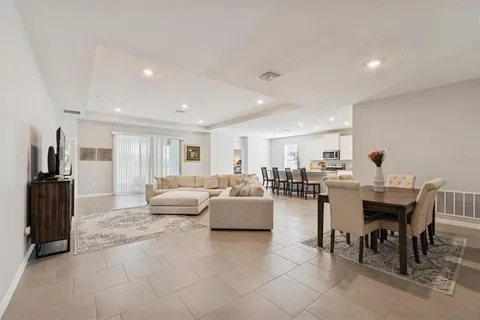 a living room with furniture and a dining table with wooden floor