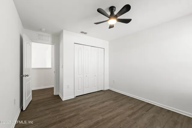 an empty room with wooden floor and ceiling fan