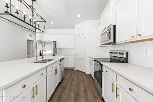 a kitchen with a sink dishwasher a stove and a refrigerator with wooden floor