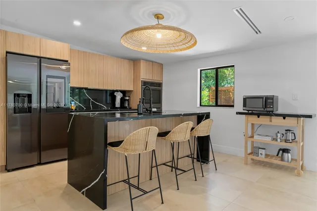 a kitchen with stainless steel appliances kitchen island granite countertop a sink and a refrigerator
