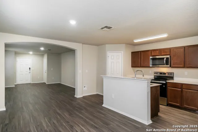 a view of a kitchen with stainless steel appliances a sink cabinets and wooden floor
