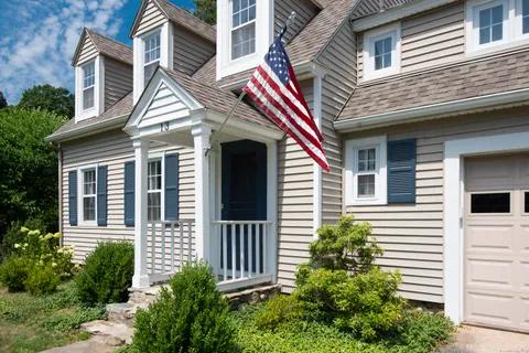 a view of a white house with a small window and potted plants