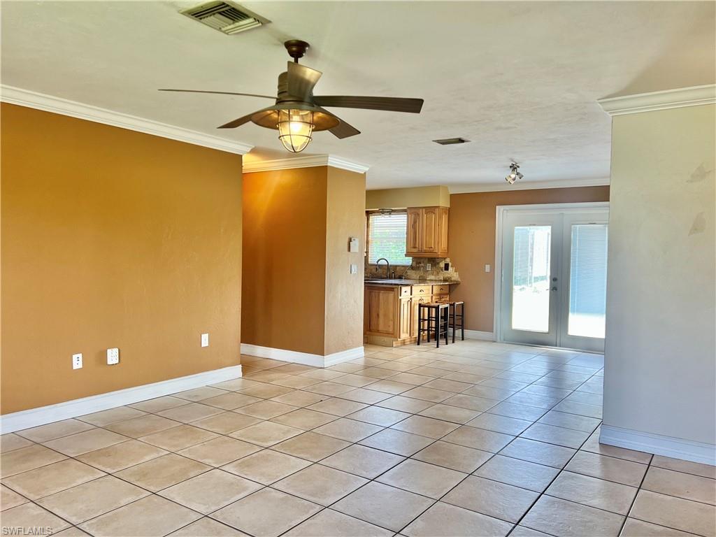 18581 Tampa Road Fort Myers, FL 33967 - Photo 9 of 25 Unfurnished living room with french doors, ceiling fan, crown molding, sink, and light tile patterned flooring