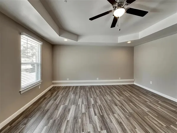 an empty room with wooden floor fan and windows