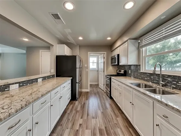 a large kitchen with stainless steel appliances granite countertop a lot of counter space and a sink