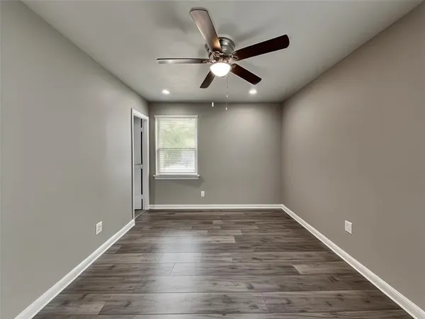 an empty room with wooden floor fan and windows