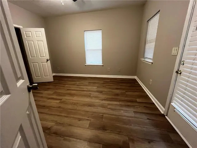 a view of an empty room with wooden floor and stairs