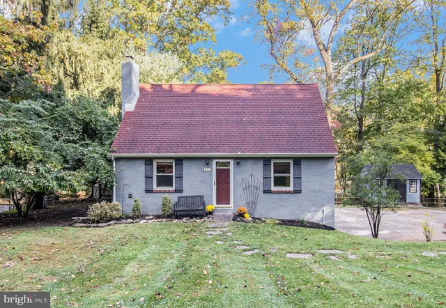 a backyard of a house with plants and large tree