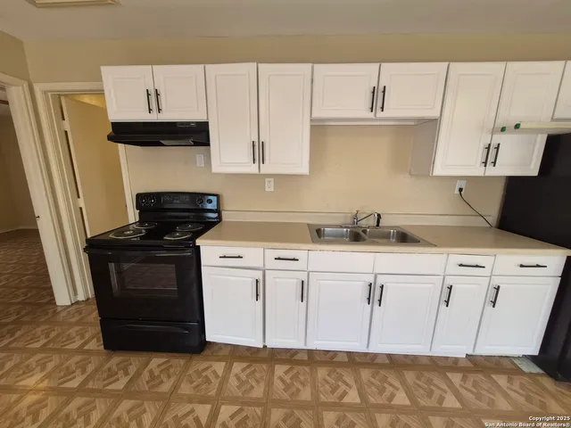 a kitchen with stainless steel appliances granite countertop a refrigerator sink and white cabinets