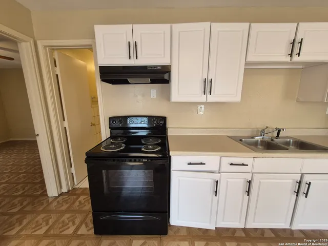 a kitchen with granite countertop white cabinets and black appliances