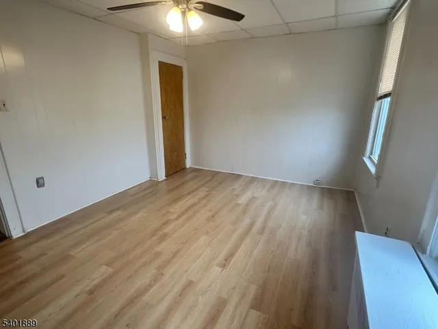 an empty room with wooden floor and chandelier fan