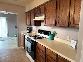 a kitchen with stainless steel appliances a stove a refrigerator a sink dishwasher and wooden cabinets with wooden floor